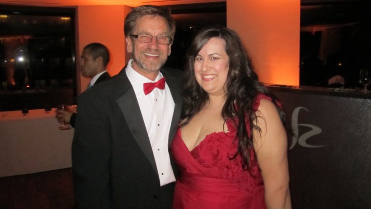 Thomas Randele wearing a suit and red tie with his daughter wearing a red dress