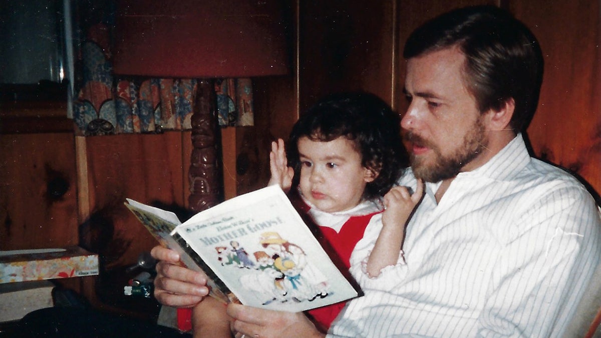 Thomas Randele reading a childrens book to his baby girl