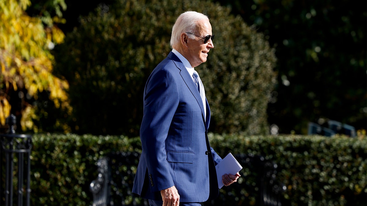 President Joe Biden with his shadow walking on the White House Lawn