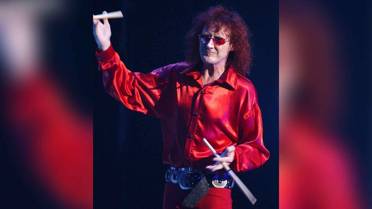 Colin Burgess with long red hair, red glasses, in a red outfit