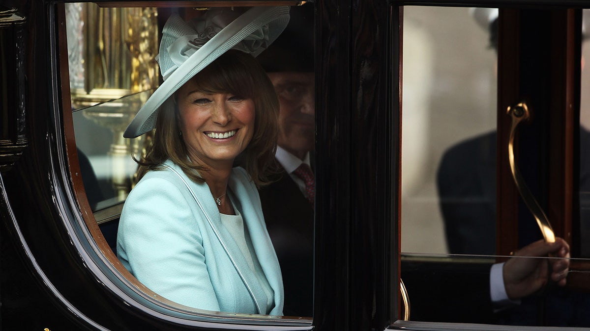 Carole Middleton wearing a powder blue suit and matching hat sitting inside a royal carriage
