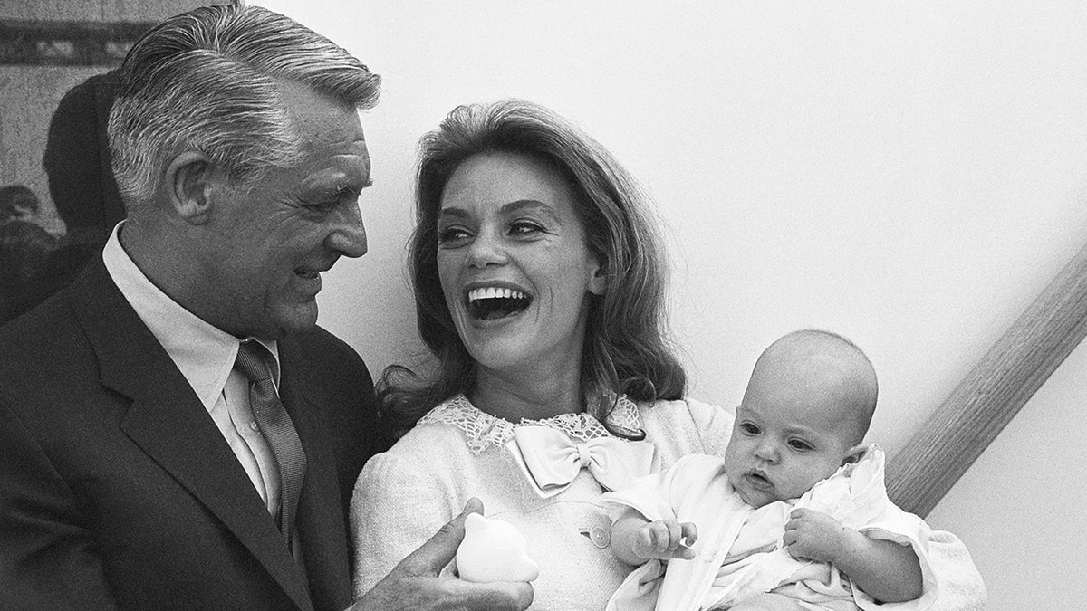 Cary Grant and Dyan Cannon laugh as Dyan Cannon holds Jennifer Grant's baby