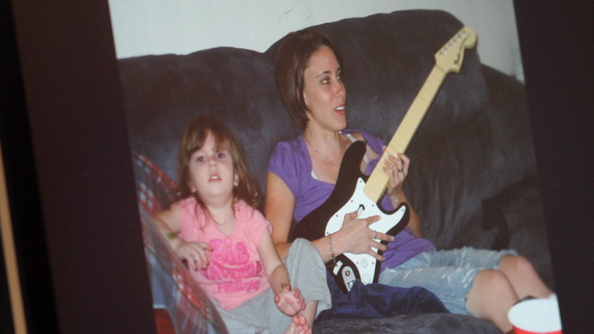 Caylee Anthony sitting next to her mother Casey Anthony playing the guitar