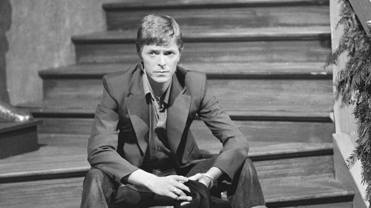 David Bowie sitting on steps looking serious