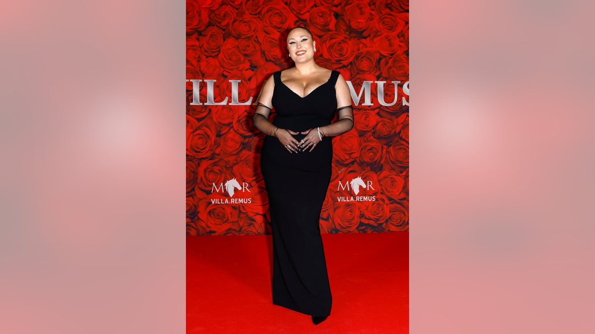 Hayley Hasselhoff wearing a black dress against a roses background