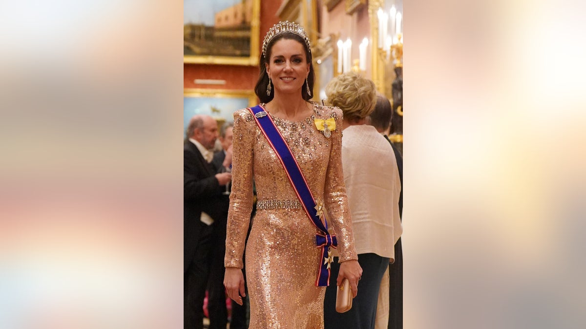 Kate Middleton wearing a sparkling pink dress, a blue and red sash and a lovers knot tiara