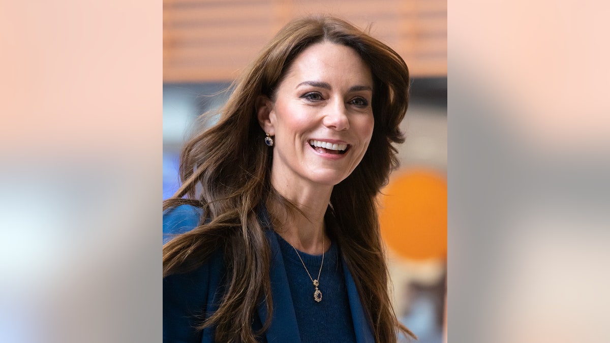 A close-up of Kate Middleton smiling with her hair blowing in the wind