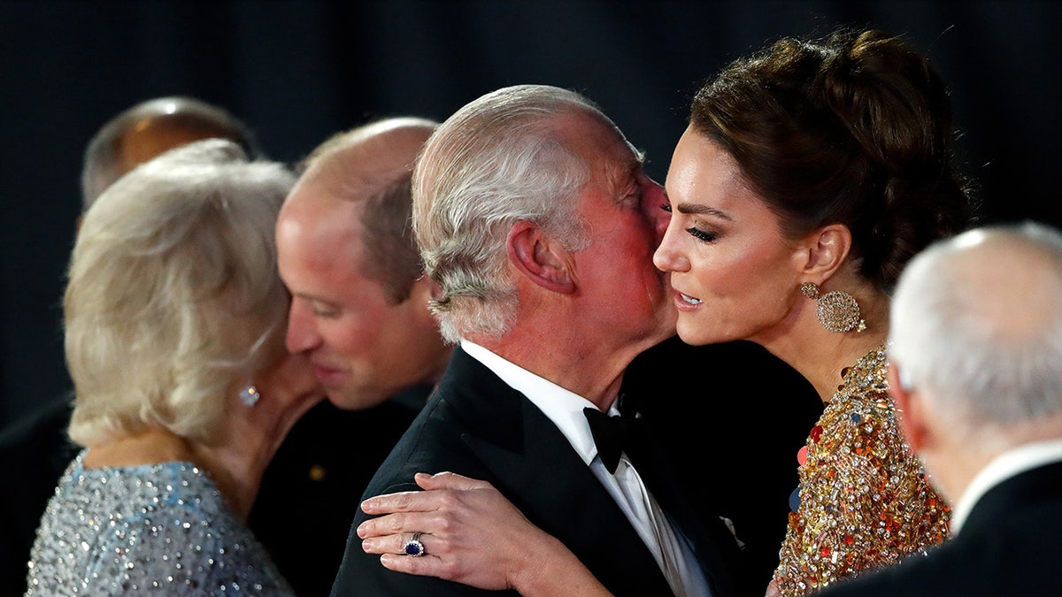 King Charles receiving a kiss on the cheek from Kate Middleton