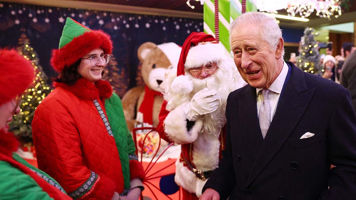 King Charles smiling next to Santa and his elves