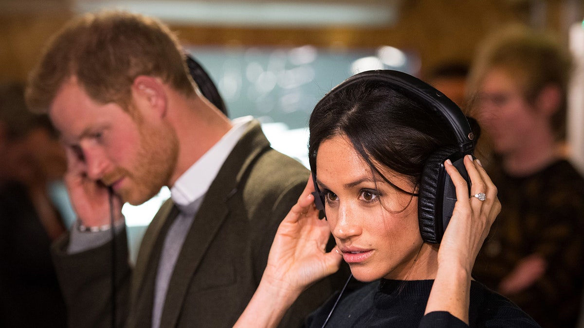 Meghan Markle and Prince Harry listening to headphones