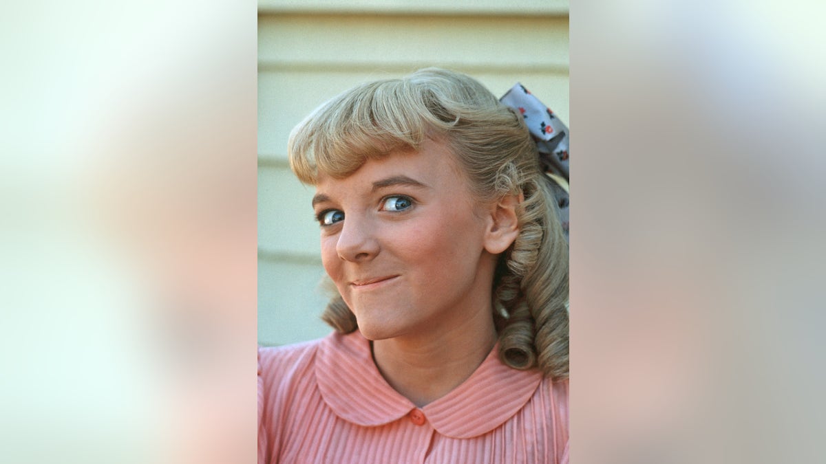 A close-up of Alison Arngrim wearing a pink dress as Nellie Oleson