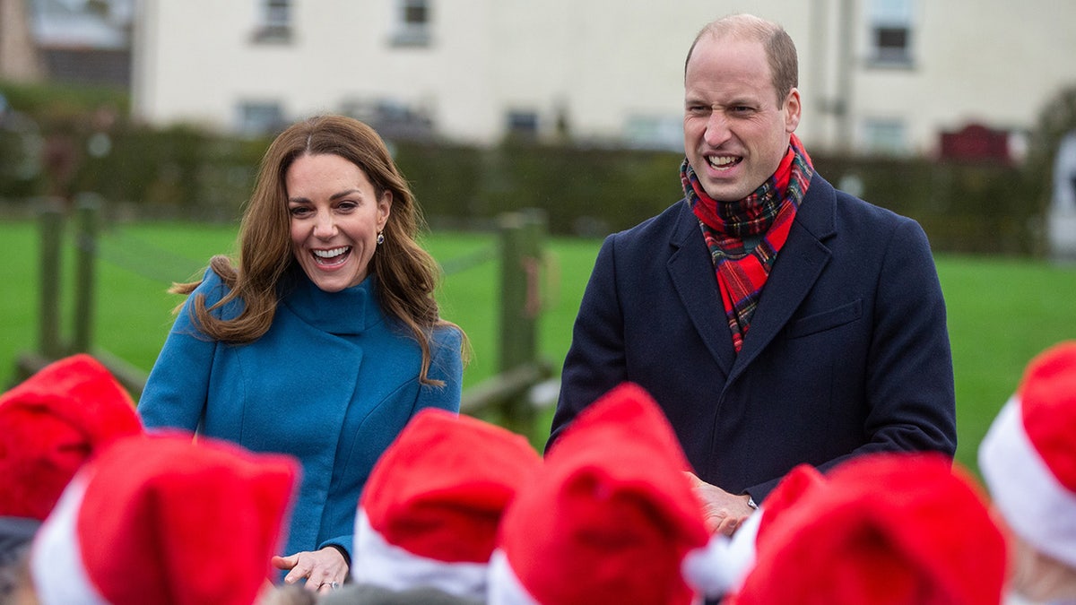 Kate Middleton and Prince William bundled up and laughing at a crowd of little Santas