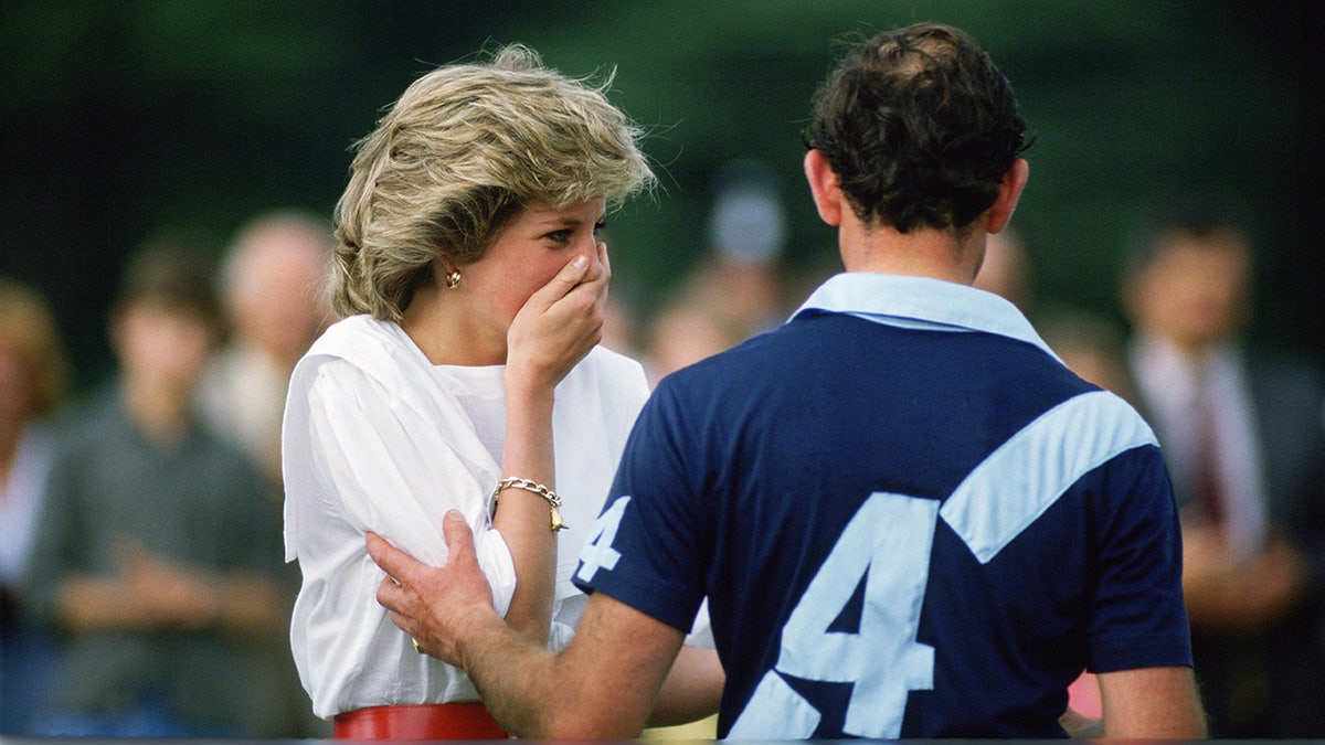 Princess Diana covering her mouth as Prince Charles stares at her