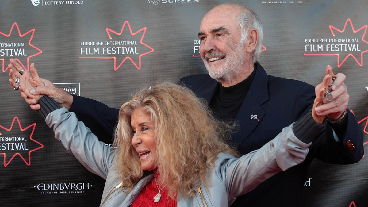 Sean Connery holding his wifes arms open