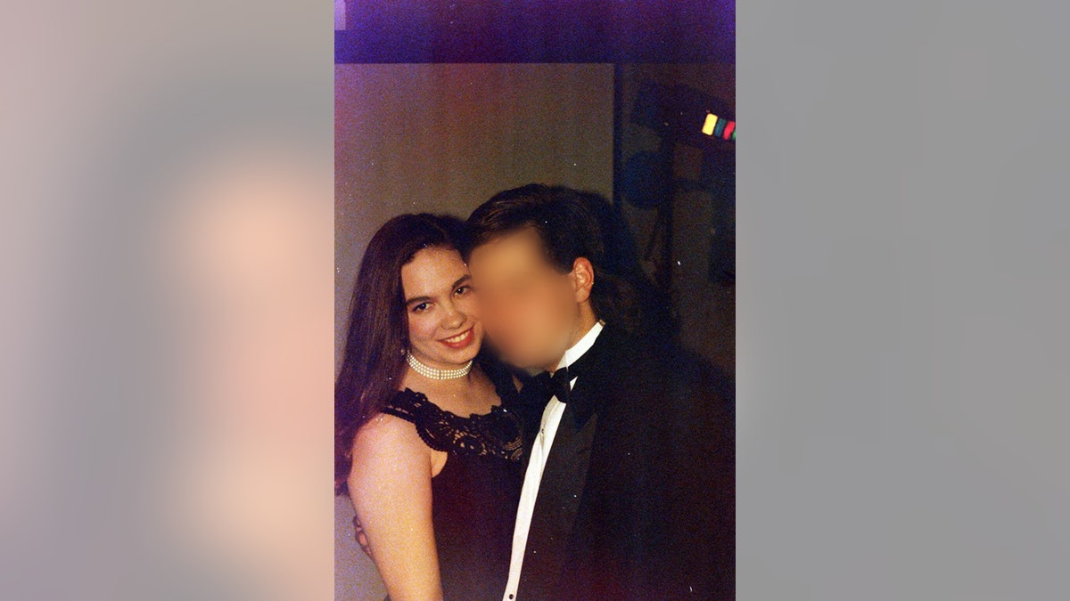 Leslie MacKool wearing a black dress and a pearll choker next to an unidentified guy in a suit and bow tie