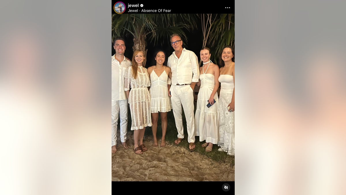 Group photograph of Jewel and Kevin Costner pinch others each wearing white