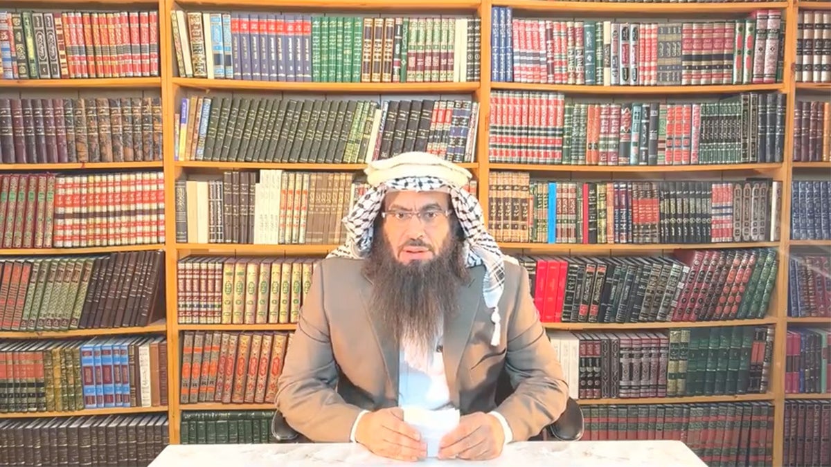 Islamic scholar Ahmad Musa Jibril at table with library backdrop