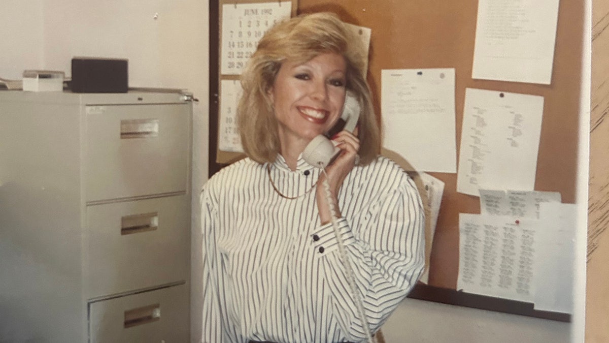 Jana Monroe smiling and holding a telephone