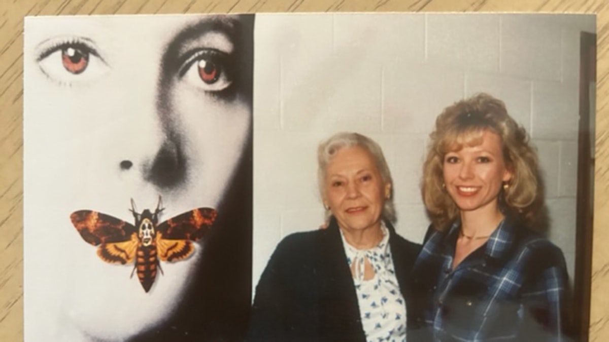 Jana Monroe smiling next to a woman and a poster for the movie The Silence of the Lambs