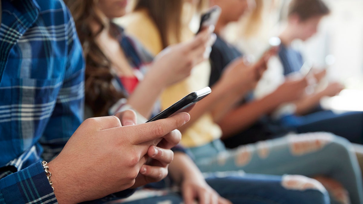 Students' hands using iPhones.