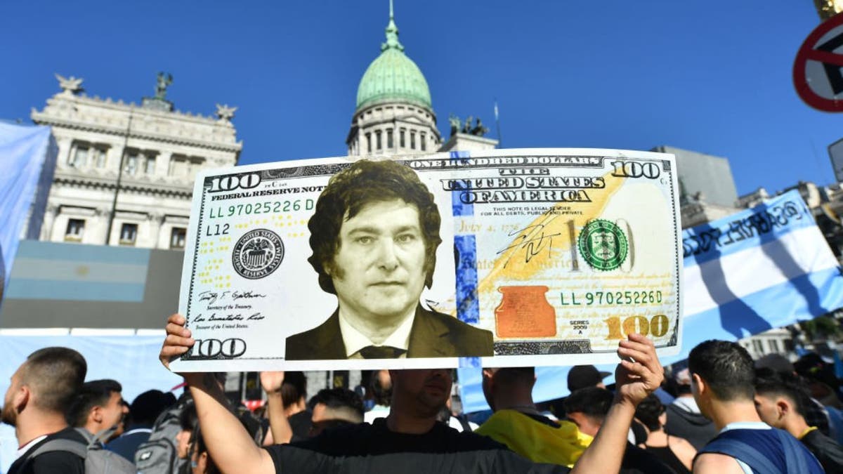 Čovjek drži ogromni znak američkog dolara s argentinskim predsjednikom Javierom Mileijem