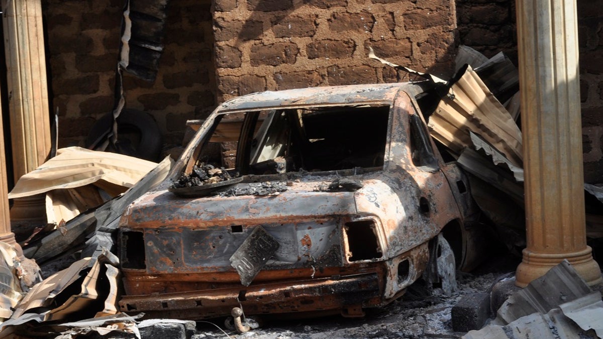 A burnt vehicle at a burnt out Nigerian home