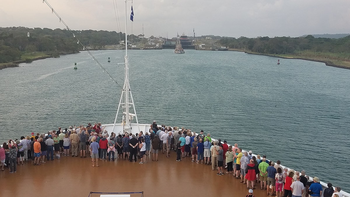 People standing by watching while a cruise ship approaching the Panama Canal entry