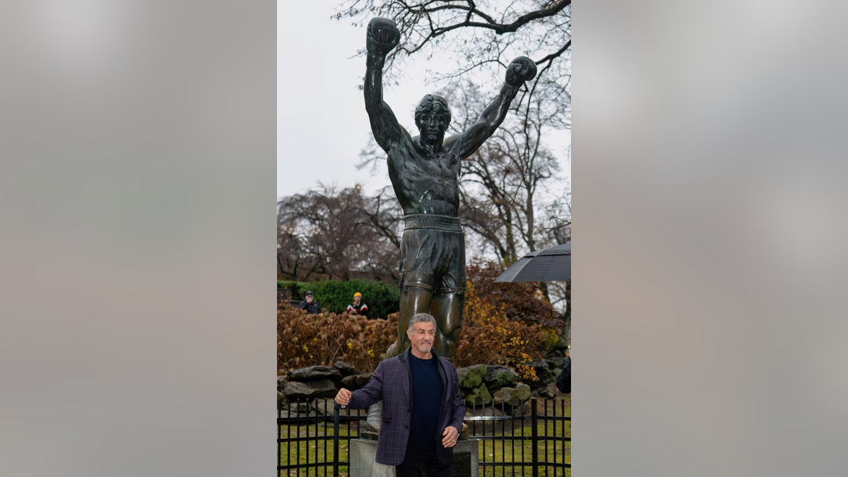 Sylvester Stallone posing with the Rocky Statue