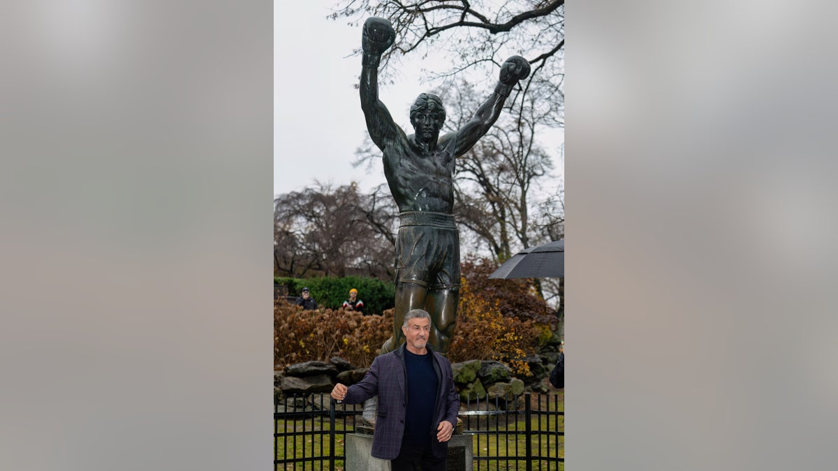 Sylvester Stallone posando con la estatua de Rocky