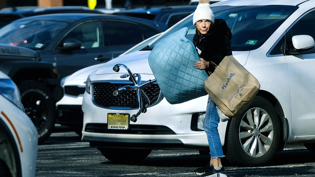 Theresa Nist carries a chair through a parking lot.