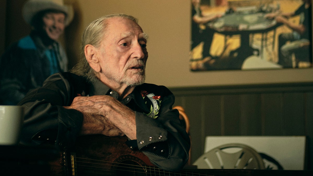 Willie Nelson sitting in a room with his guitar