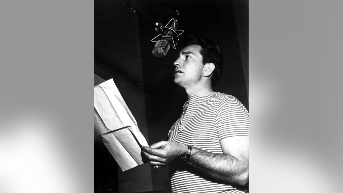 Black and white photo of Willie Nelson singing in recording booth