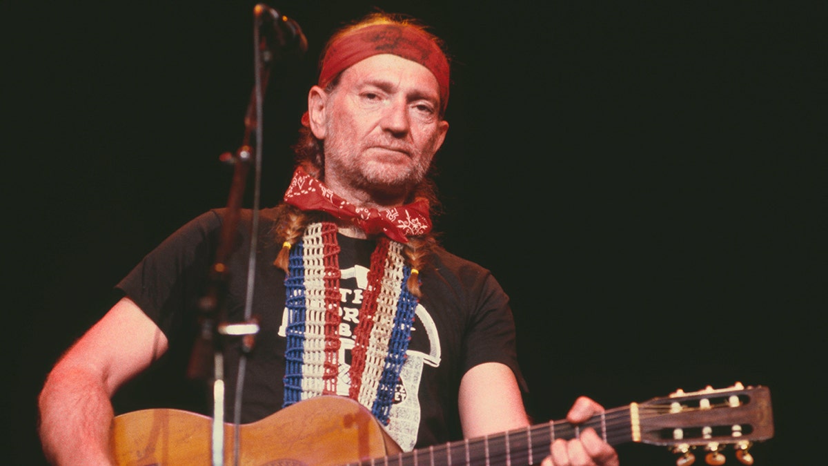 Willie Nelson performing on stage with guitar