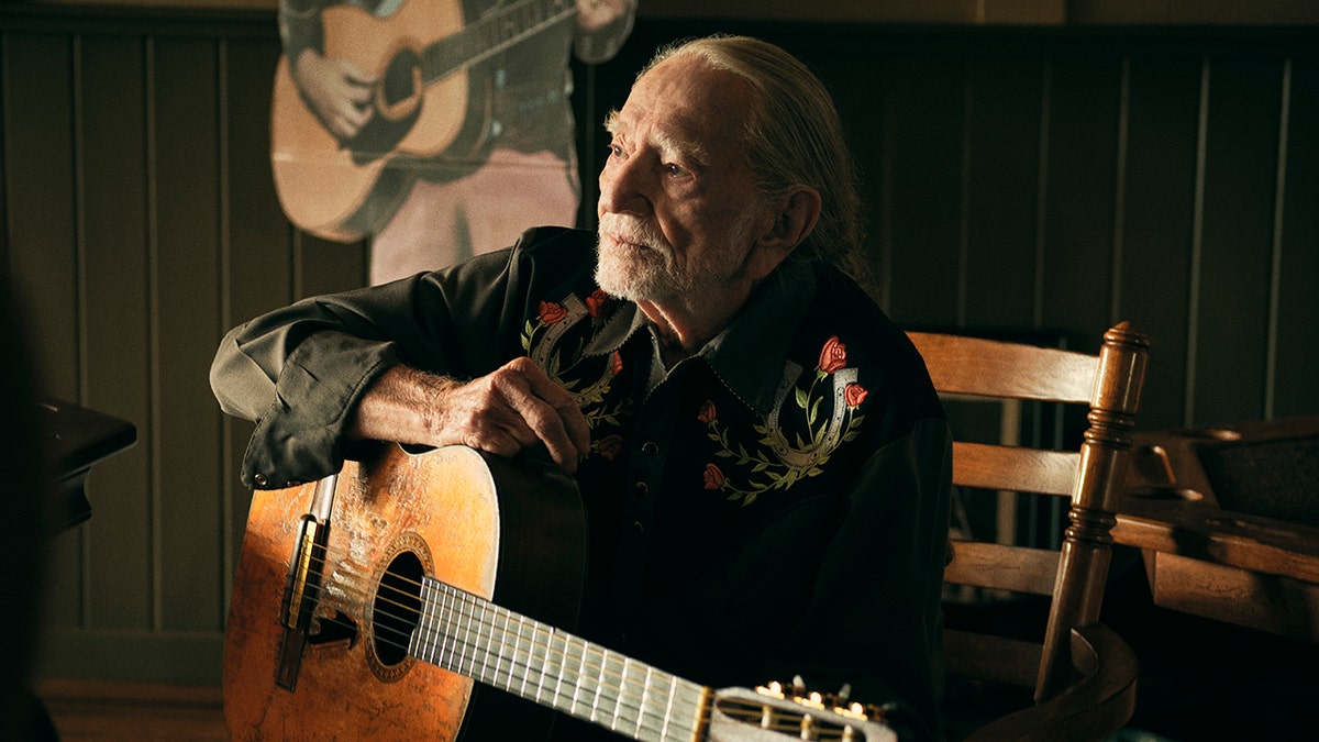 Willie Nelson sitting with his guitar
