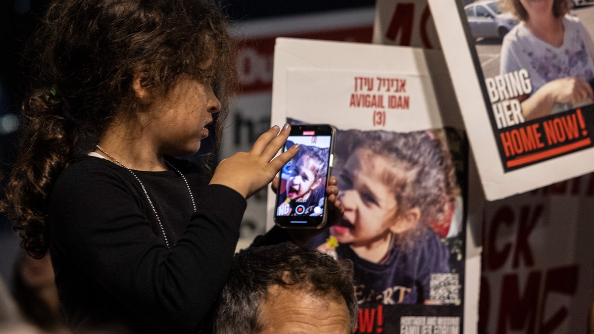  Una niña toma una fotografía de un cartel en el que aparece la rehén Abigail Edan, una niña de 4 años con ciudadanía estadounidense e israelí que fue tomada como rehén el 7 de octubre.