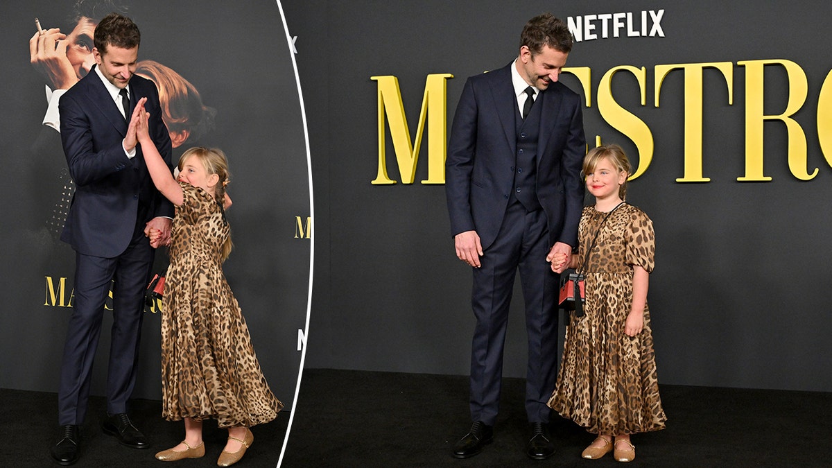 Bradley Cooper em um terno azul escuro dá a sua filha Lea em um vestido com estampa de leopardo um high five split Bradley Cooper segura a mão dela no tapete