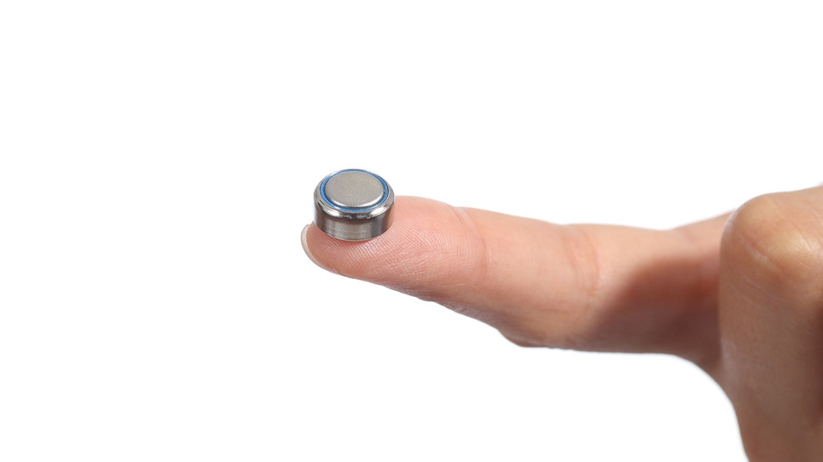 Woman hand holding a button battery with the forefinger