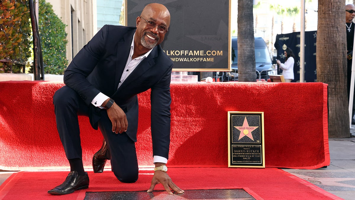 Darius Rucker kneels down next to his Hollywood star