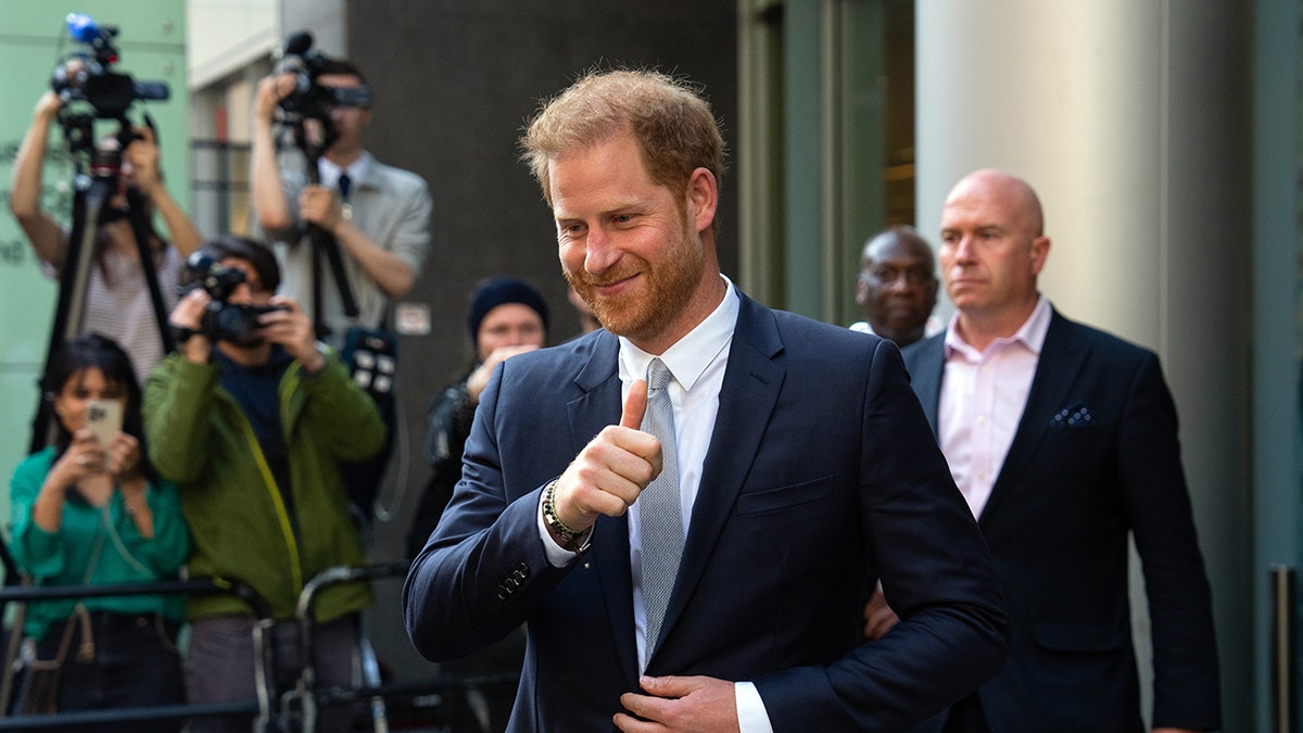 Prince Harry giving a thumbs out outside of court in front of photographers