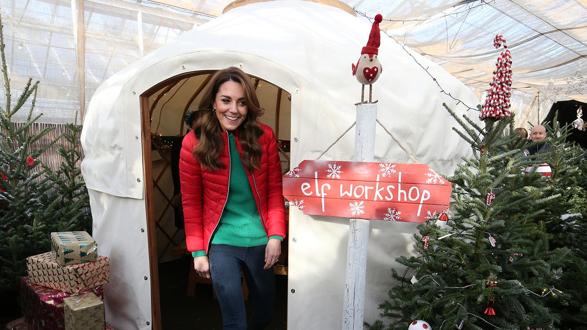 Kate Middleton stepping out of an elf workshop with a red sweater and a green shirt