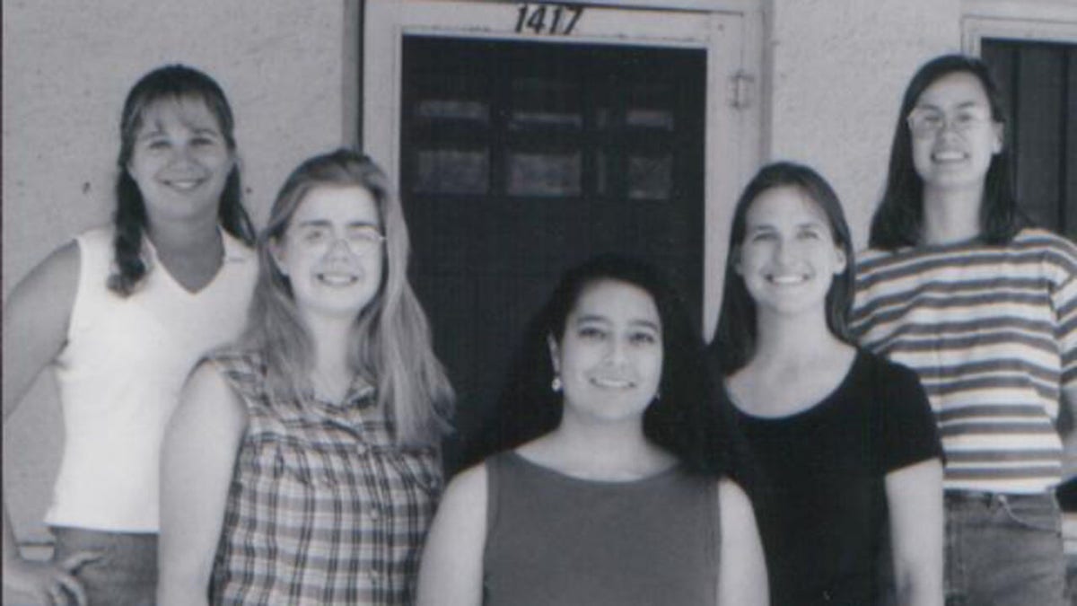 Five young women posing in front of a door
