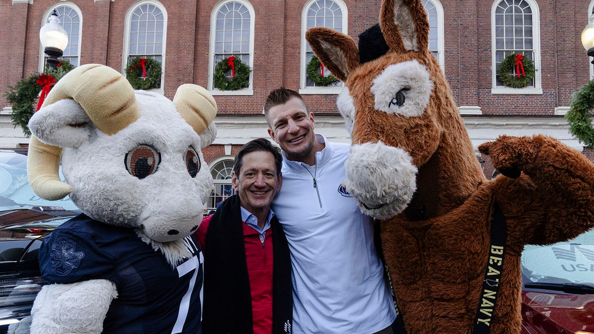 Patriots legend Rob Gronkowski helps USAA gift two veterans vehicles ahead of 124th Army-Navy Game 1 USAA CEO Wayne Peacock and NFL legend Rob Gronkowski pose with Army and Navy mascots