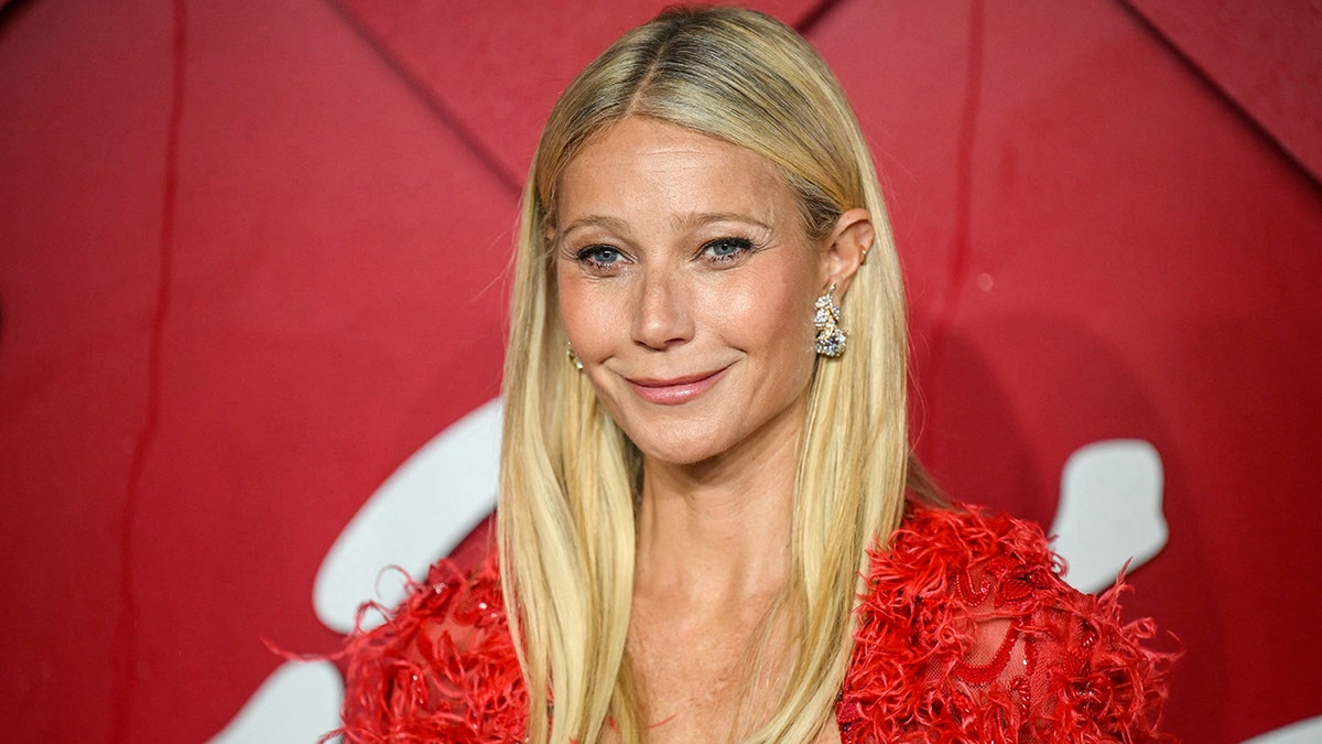 Gwyneth Paltrow in a red dress with roses smiles demurely