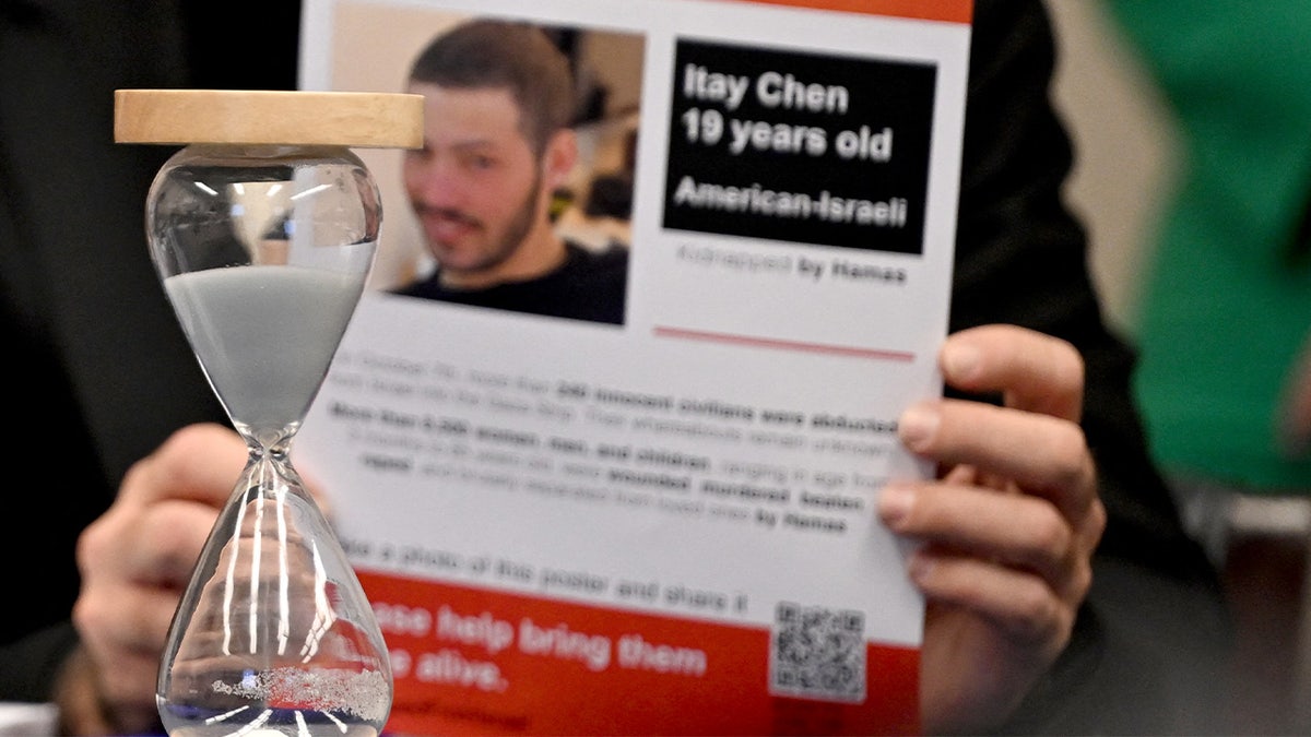 An hourglass sits in front of a "kidnapped" flier showing a photo of 19 year old Itay Chen, during a US House Committee on Foreign Affairs Subcommittee on the Middle East, North Africa, and Central Asia roundtable.