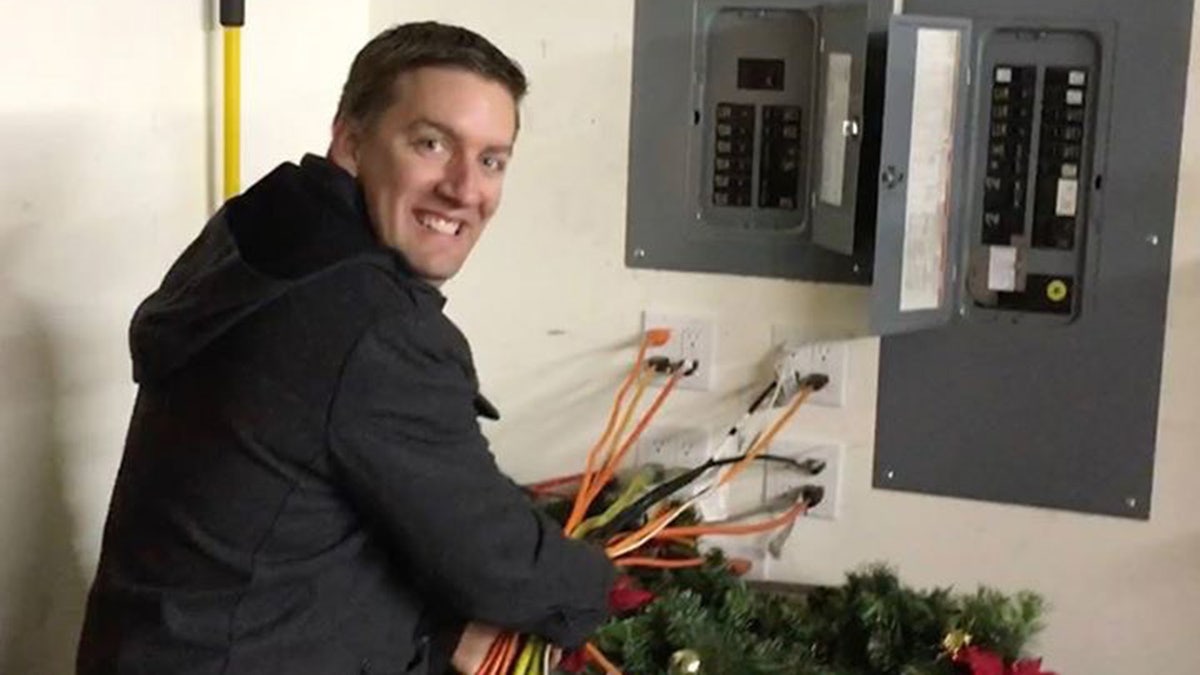 Jeremy Morris holds numerous extension cords plugged into wall