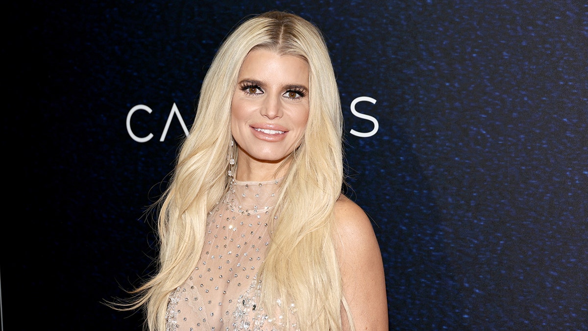 Jessica Simpson smiles wearing a nude colored body suit with sparkles on it