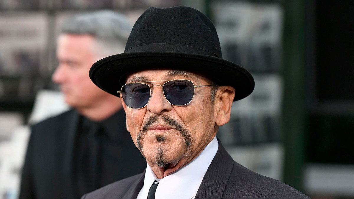 Joe Pesci in a suit with a black hat and black lensed sunglasses on the carpet