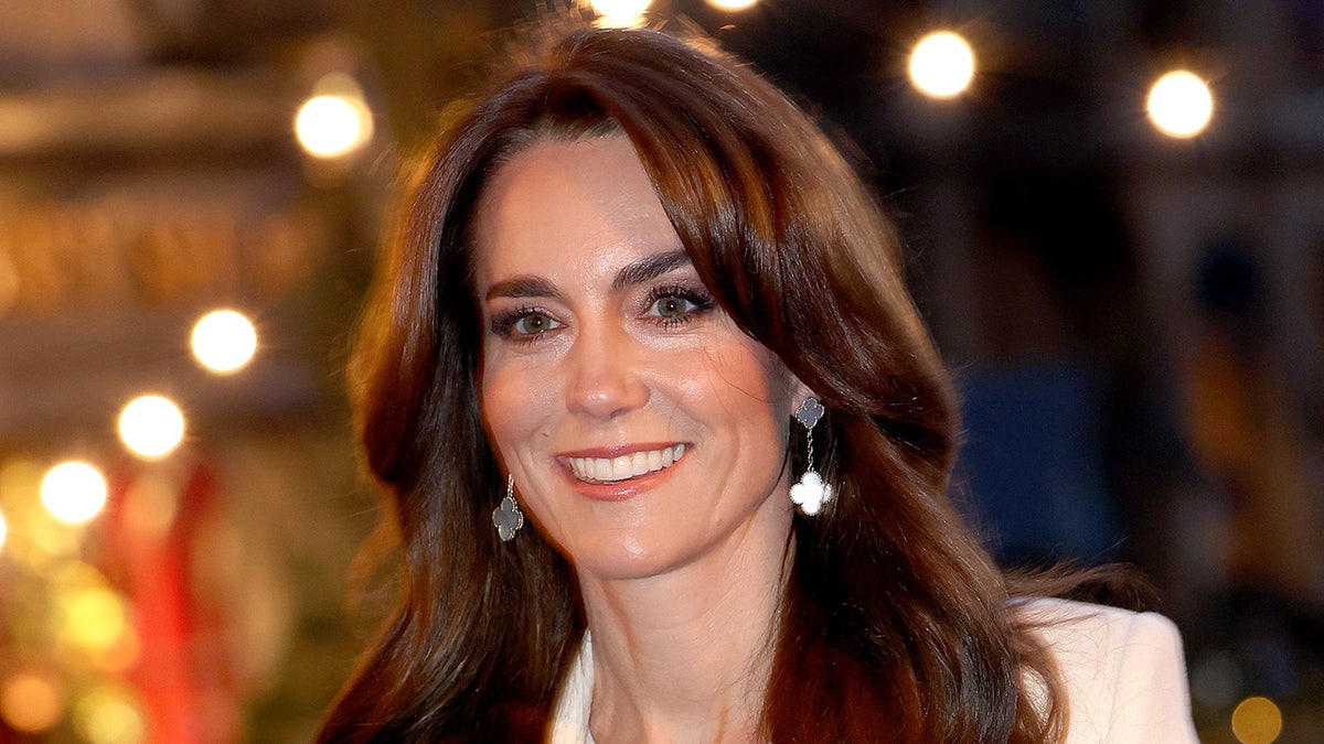 Kate Middleton sorrindo do lado de fora do serviço de canções de natal