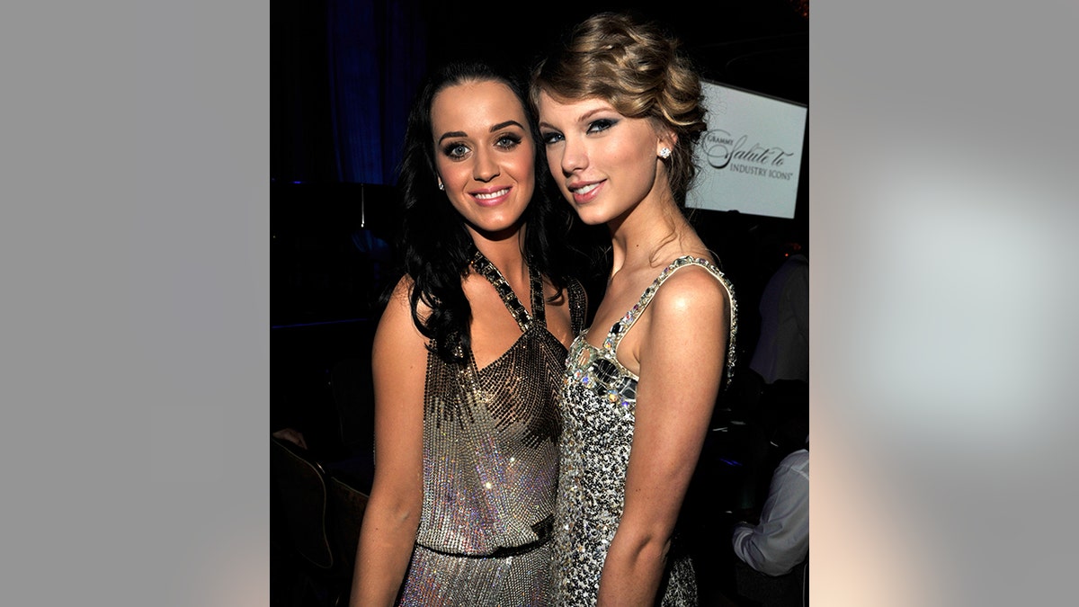 Katy Perry in a halter dress smiles next to Taylor Swift in a sparkly dress at an event for the Grammys