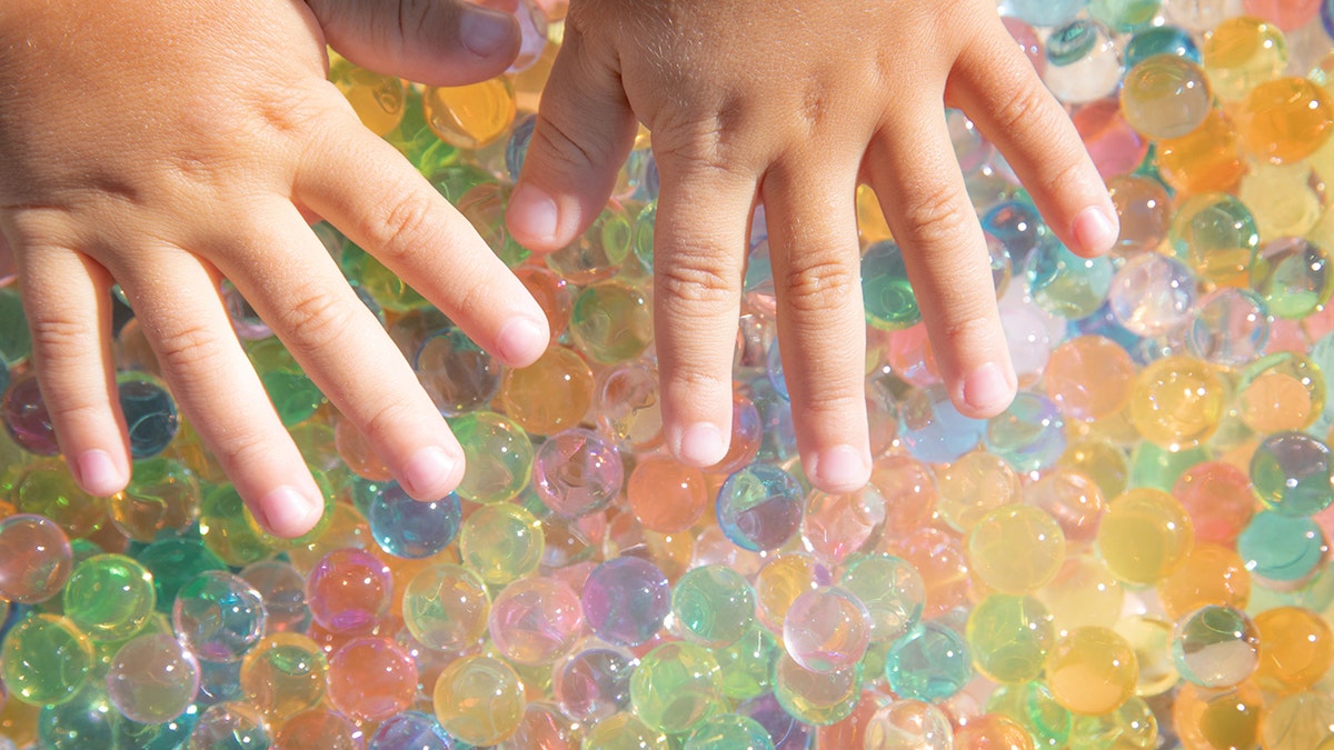 Colored balls of hydrogel touch children's hands. Sensory sensations
